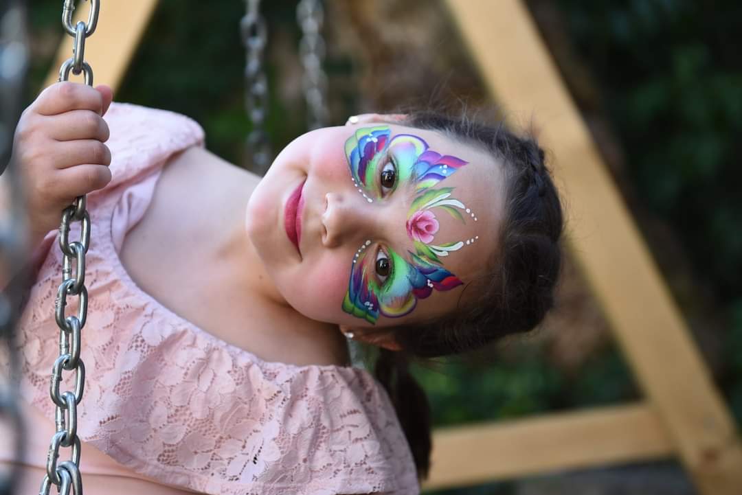 Devojčica sa šminkom avatara na licu, ljulja se na ljuljašci